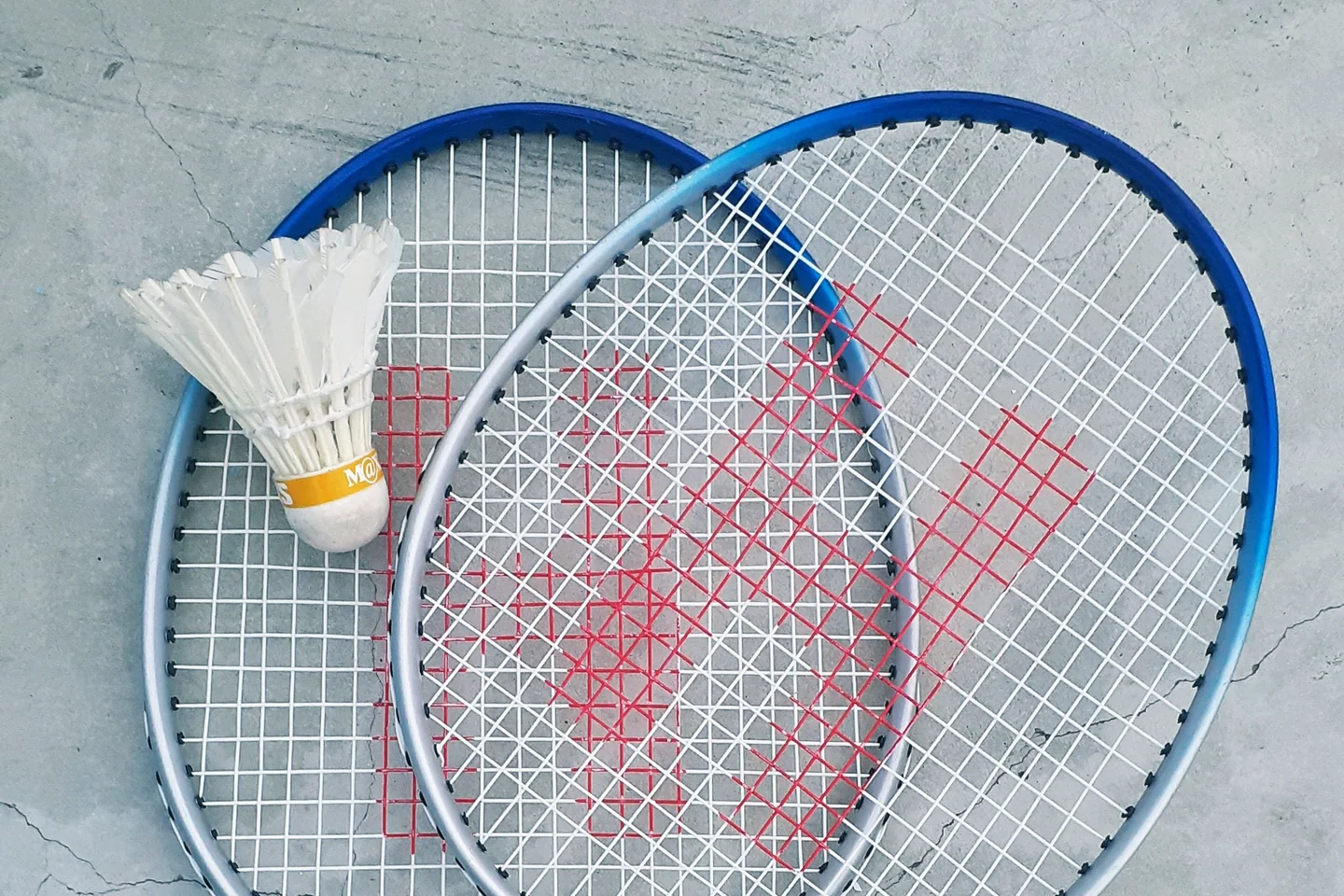 Dos raquetas de bádminton y un volante sobre una superficie de cemento