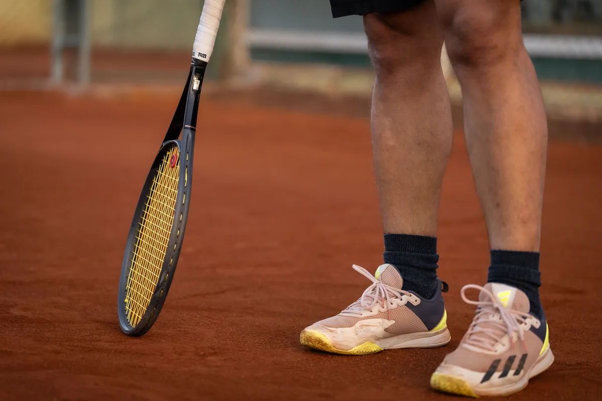 Toprak kortta tenis ayakkabıları ve raket
