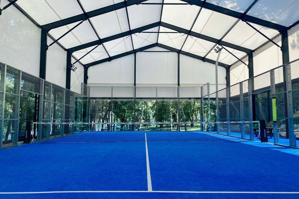 Cam ve metal telle çevrili mavi kapalı padel kortu