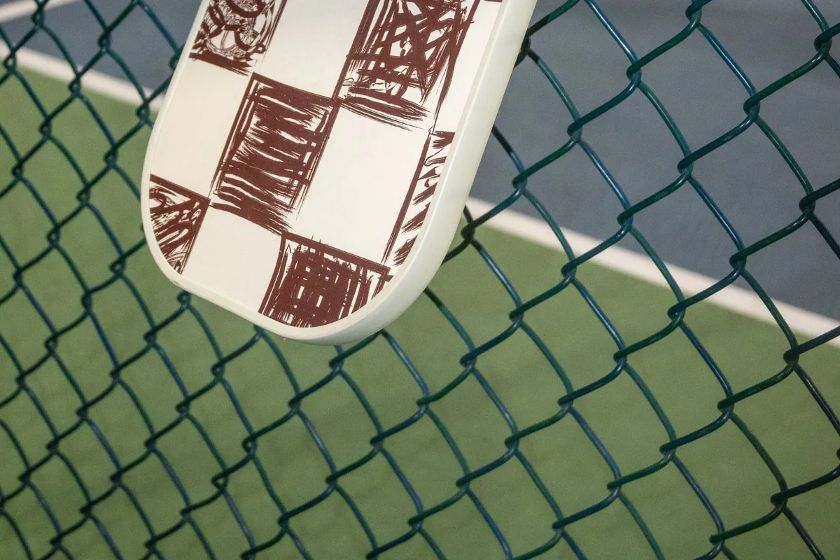 Tel örgüye asılmış kare desenli pickleball raketi