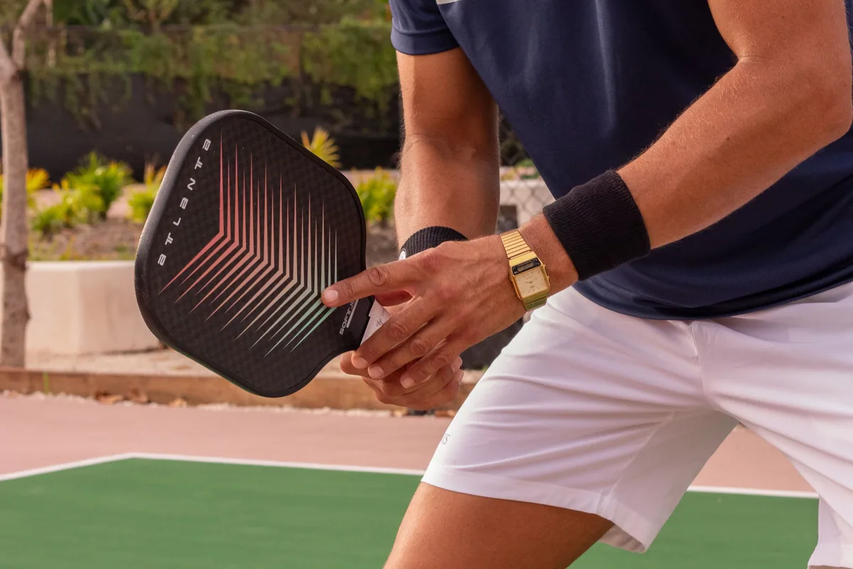 Açık kortta düz yüzeyli pickleball raketi tutan bir oyuncu