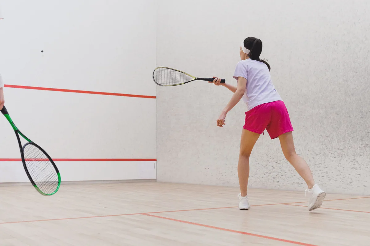 Jugadora golpeando la pelota en una pista de squash