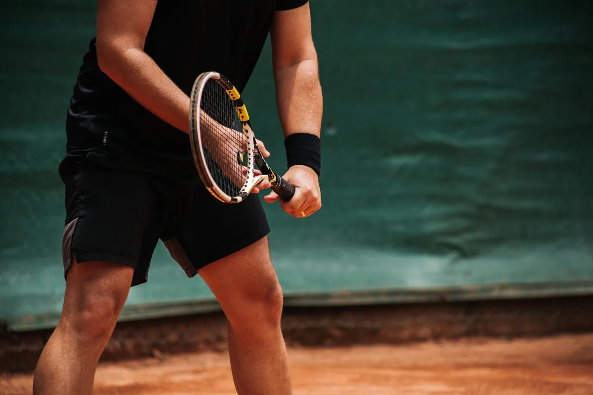 Toprak kortta tenis raketini tutan eller