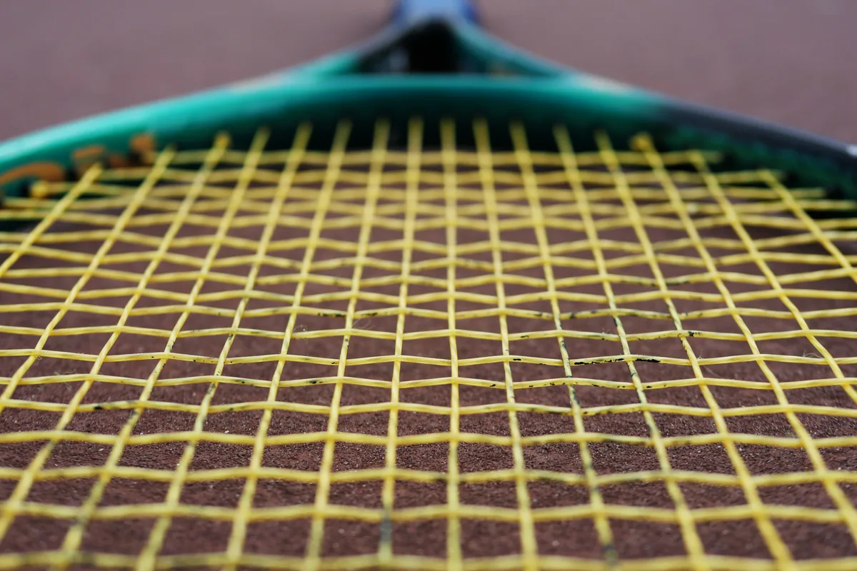 Tenis raketindeki sarı kordajların yakın görünümü
